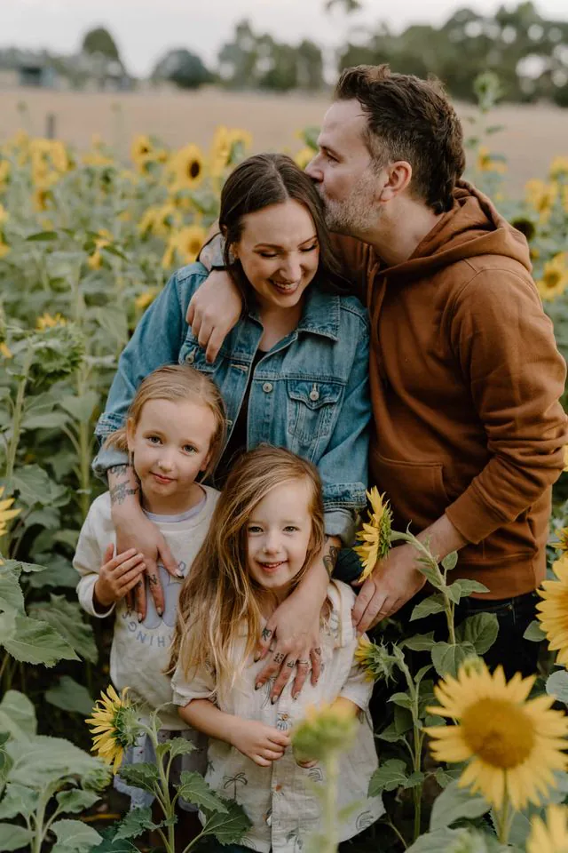 Gareth with his wife and kids in a sunflower field at golden hour