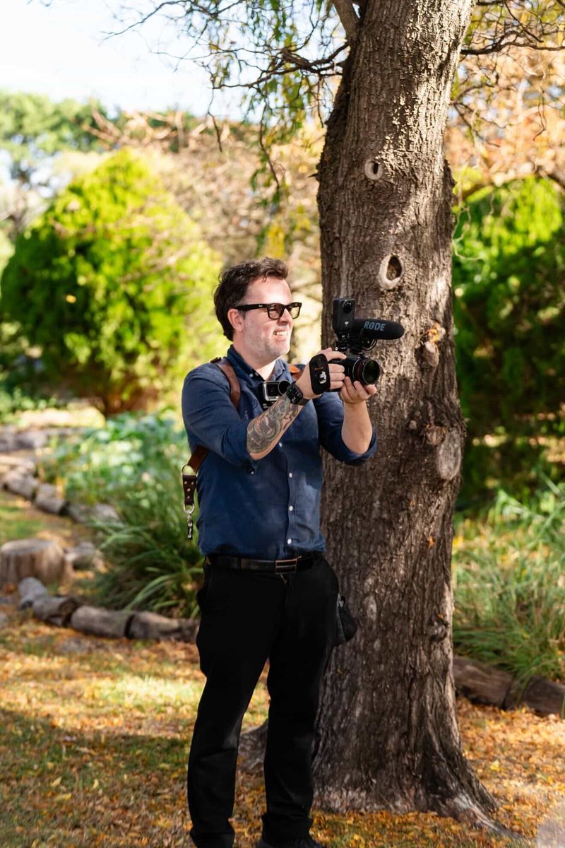 Gareth filming with a shotgun mic beside a tree